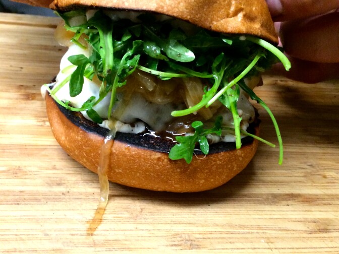 The Truffle Burger: A grass-fed patty, muenster cheese, arugula dressed in truffle oil, caramelized onions cooked down with beer and garlic aioli, all on a brioche bun.