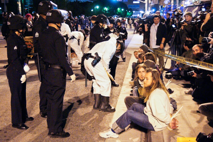 Arrested protesters from the Occupy LA movement are lined up on a curb next to the Police Administration Building while they are questioned.