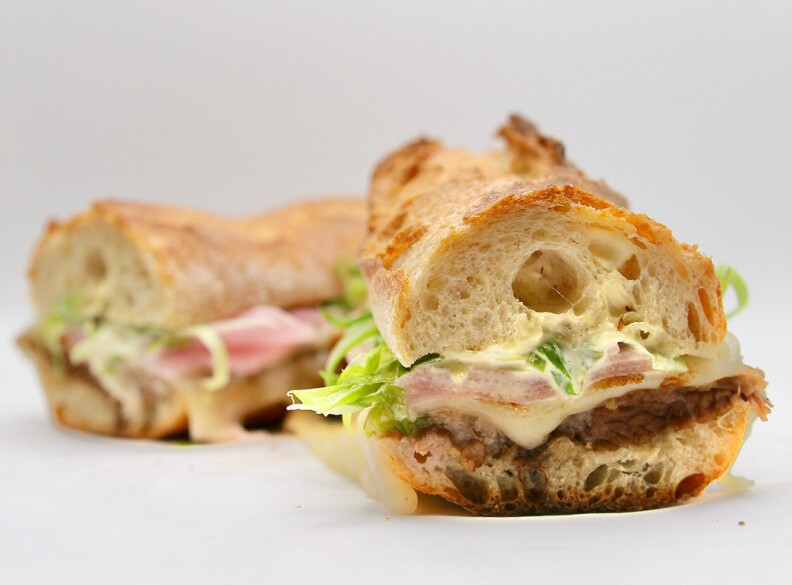 The Normandie brisket sandwich from Open Market cut in half is seen close-up.