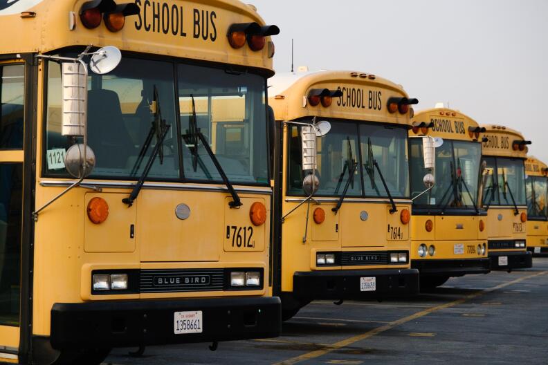 Yellow school busses lined up in a bus yard.