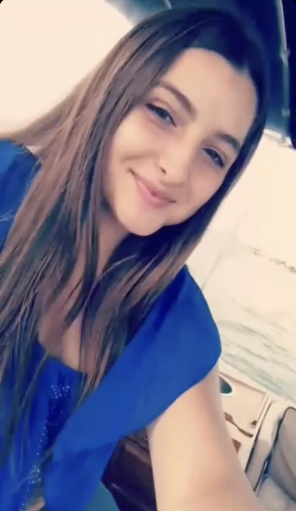 An image of a woman with straight hair and a blue top. 