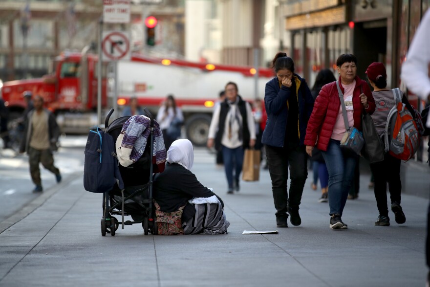 SAN FRANCISCO, CALIFORNIA - NOVEMBER 25: A homeless woman begs for change as pedestrians walk by on November 25, 2019 in San Francisco, California. The Trump administration could be preparing to replace recently dismissed executive director of the U.S. Interagency Council on Homelessness Matthew Doherty and deliver a new agenda to combat homelessness in cities like San Francisco and Los Angeles. (Photo by Justin Sullivan/Getty Images)