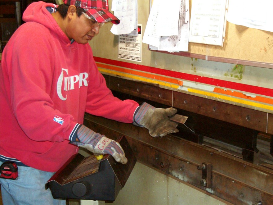 Carlos Chavez cuts sheet metal to repair a tortilla-making machine. Chavez is one of the few remaining employees at Chip Masters. Earlier this year, he agreed to reduce his hours to keep his job.