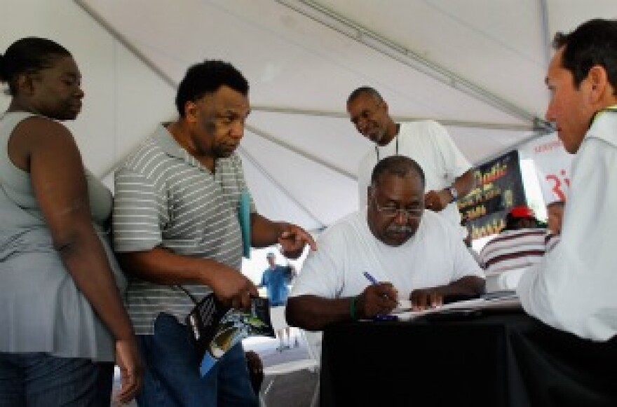 Job seekers speak with a construction company recruiter as they and others look for construction work. 