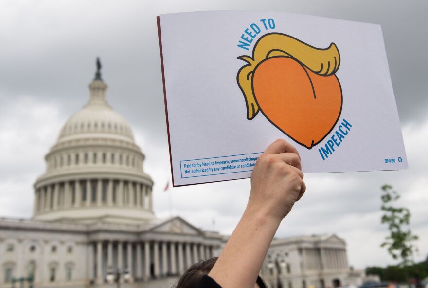 A woman holds a sign during a press conference where activist delivered a computer flash drive to lawmakers at the US Capitol in Washington, DC, May 9, 2019. - The drive contains 10 million signatures on a petition urging the US Congress to begin impeachment proceedings against US President Donald Trump. (Photo by SAUL LOEB / AFP)        (Photo credit should read SAUL LOEB/AFP/Getty Images)