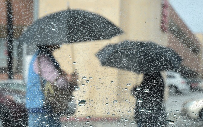 File: Women use umbrellas under a steady Los Angeles rainfall in September 2015.