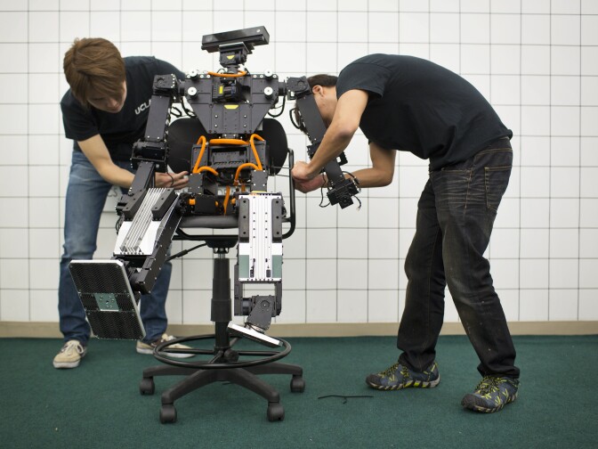 Min Sung Ahn, left, who will be a mechanical engineering grad student in the fall, and Jeong Yoon, a first-year graduate student in mechanical design, are able to place THOR in a sitting position. To transport the robot to Pomona, THOR will hang inside a large wooden box.