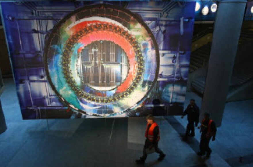 Workers walk past a giant photograph of a part of the Large Hadron Collider (LHC) at the 'Weltmaschine' ('World Machine') exhibition on October 14, 2008 in Berlin, Germany.