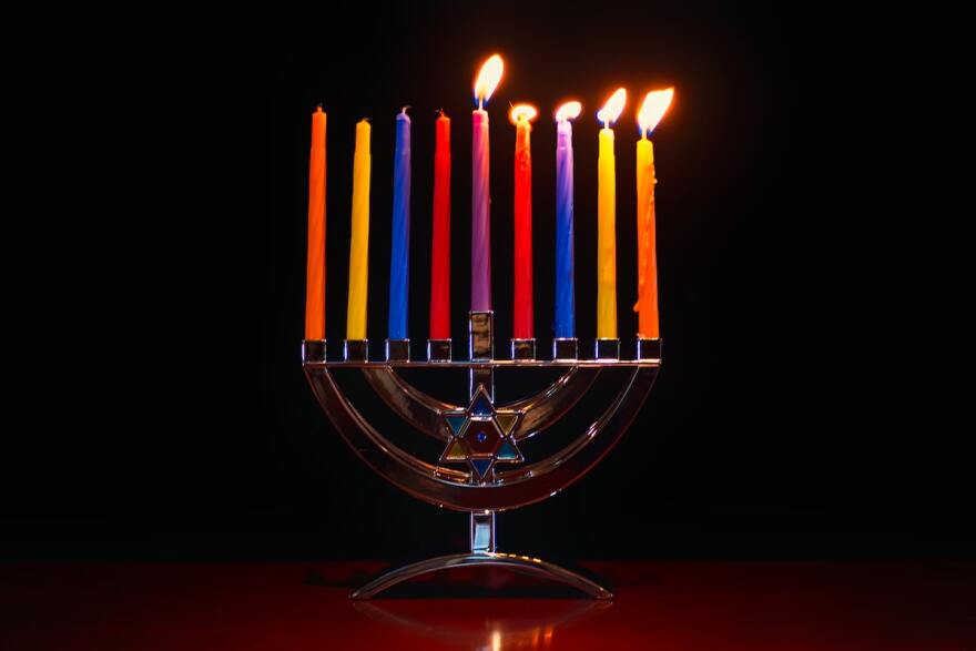 Colorful candles in a menorah, with five of them lit.