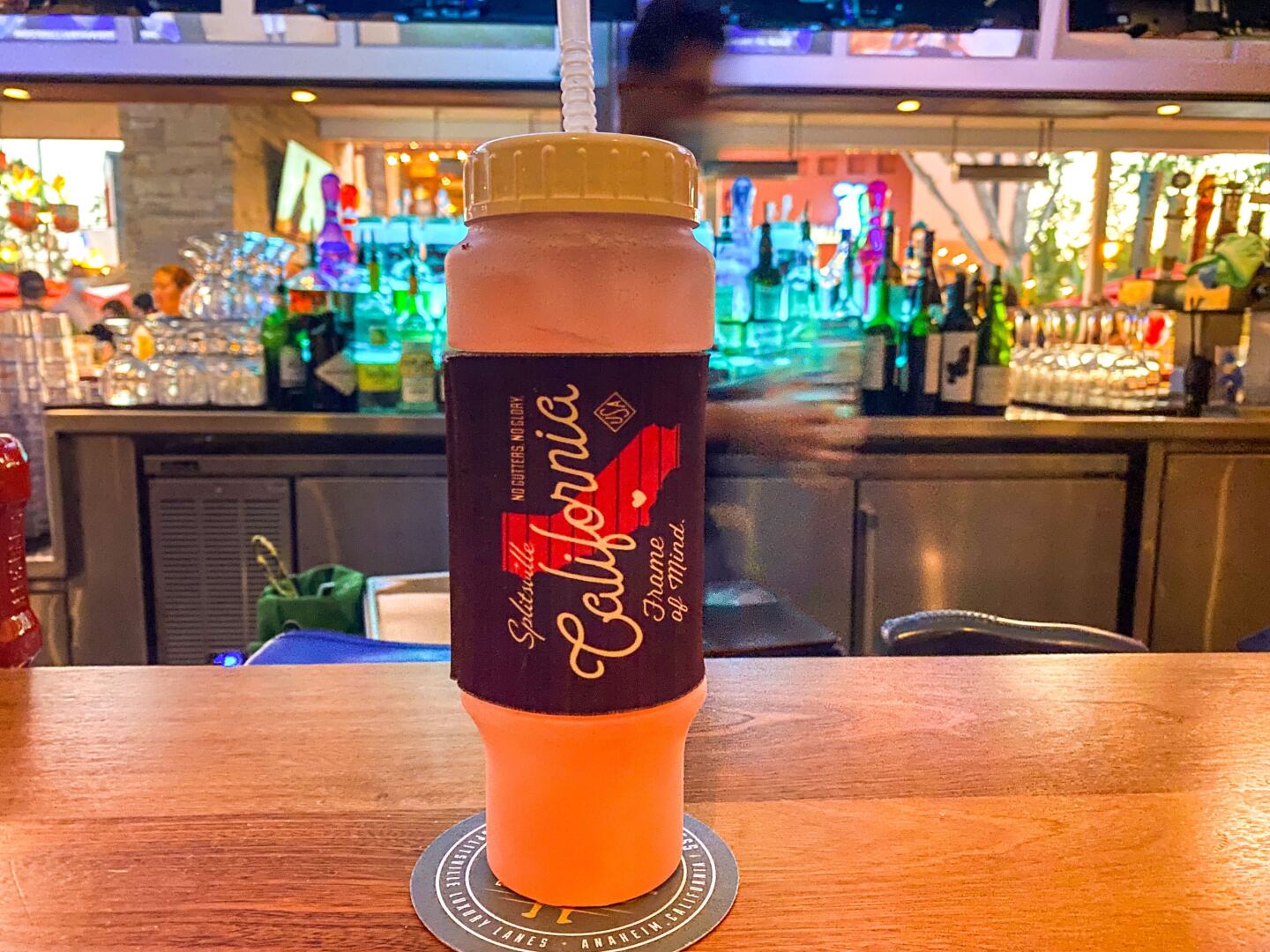 A water bottle filled with pink liquid sits on a wooden bar.