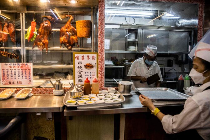 A cook (L) prepares roasted duck at a restaurant preparing Yum Cha, Cantonese brunch involving tea and dim sum.