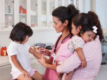 File: A mother watching a doctor giving her daughter an injection.