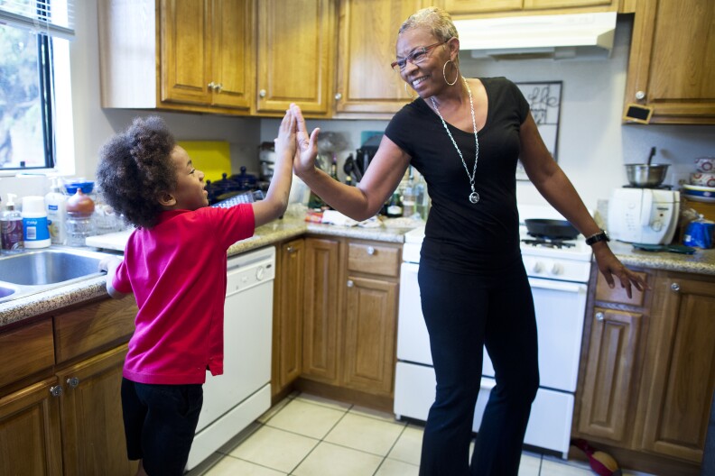 Tonia McMillian, a home-based child care provider, high-fives 6-year-old Skylar on Feb. 12 in her Bellflower home. In addition to her home care, McMillian also visits other childcare through the day as a consultant.