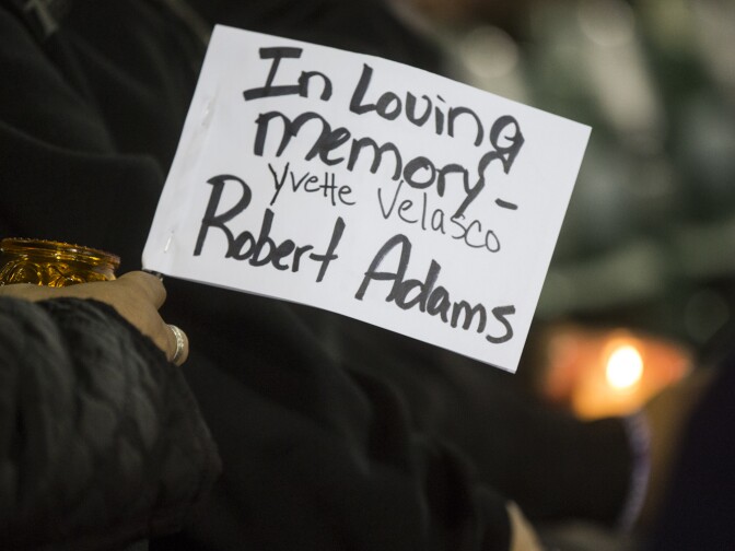 Co-workers and friends of Yvette Velasco and Robert Adams hold signs in their memory during a vigil at San Manuel Stadium in San Bernardino on Thursday night, Dec. 3, 2015 following a mass shooting that left 14 people dead and 21 injured on Wednesday at the Inland Regional Center.