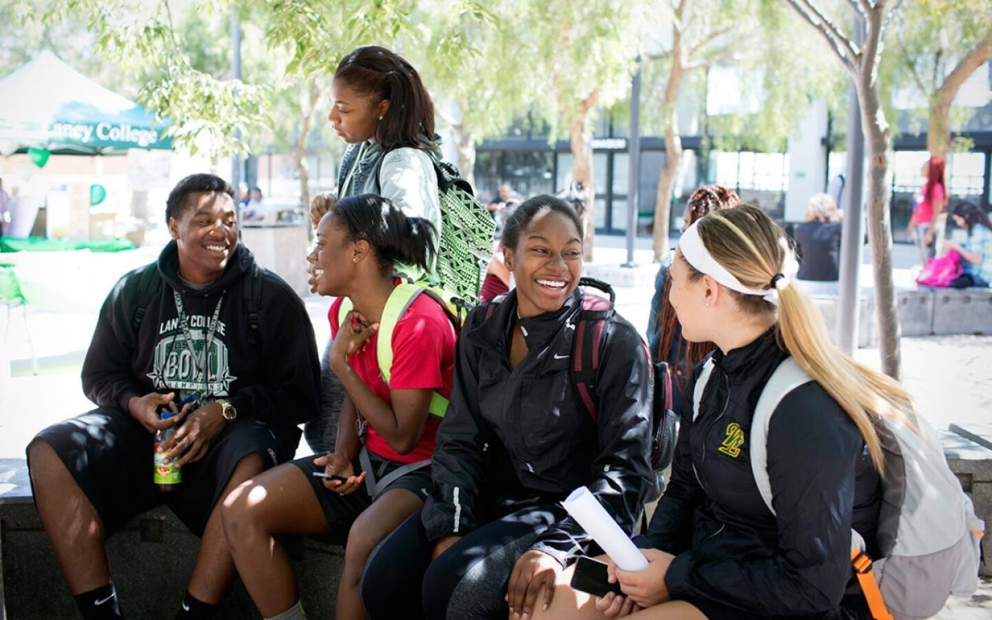 A group of students convene outside Laney College in Oakland, California. They are seen smiling at each other.