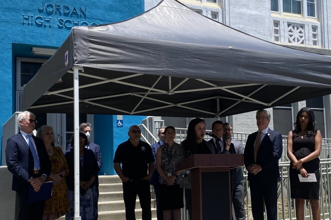 A group of speakers including LA County DA George Gascón stand under a shade awning during a press conference at Jordan High School in Watts. 