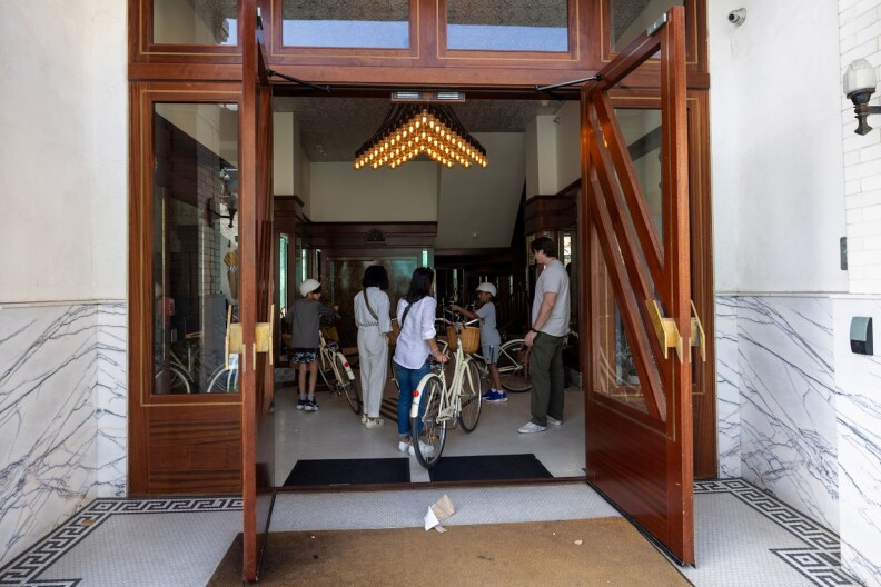 A group of people handling bicycles gather inside a building.