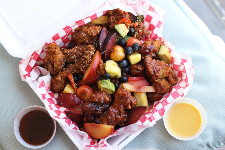 fried chicken topped with chunks of plums, avocado, pineapple, cherries and blueberries
