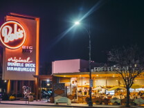 The Bob's Big Boy restaurant in Burbank at night with it's red neon sign illuminated and it's dining space lit up with people inside.