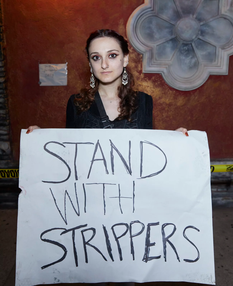 A person stands with a sign that reads: Stand with strippers