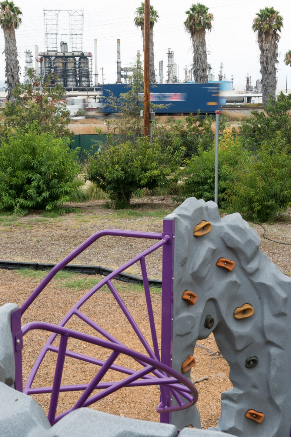 An oil refinery and highway are visible over the fence of a Long Beach child care center. KPCC reporters Deepa Fernandes and Sarah Monte investigate the effect of air pollution on early childhood development by taking air quality readings outside of child care centers located in Los Angeles County.