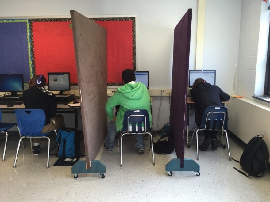 Students in the Aspire program work individually at computers separated by privacy screens. The partitions help the students feel less anxious.
