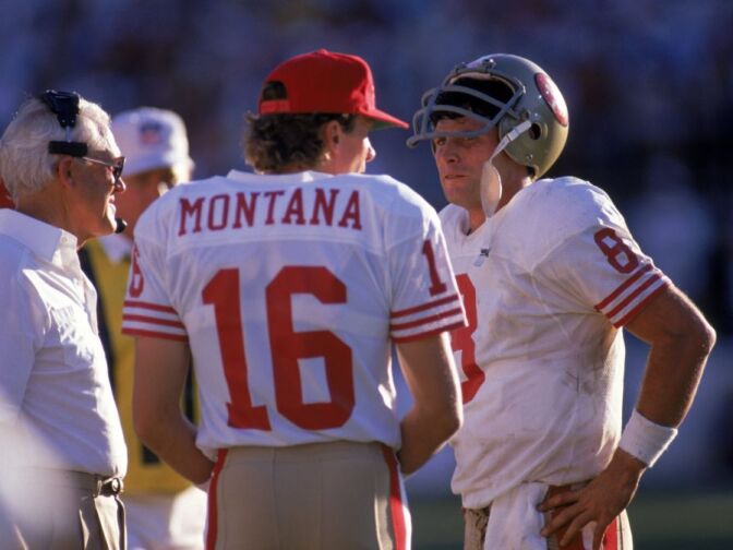 Quarterbacks Steve Young #8 and Joe Montana #16 of the San Francisco 49ers discuss strategy with head coach Bill Walsh during the game against the Phoenix Cardinals at Sun Devil Stadium on Novemer 6, 1988 in Tempe, Arizona. The Cardinals won 24-23. 
