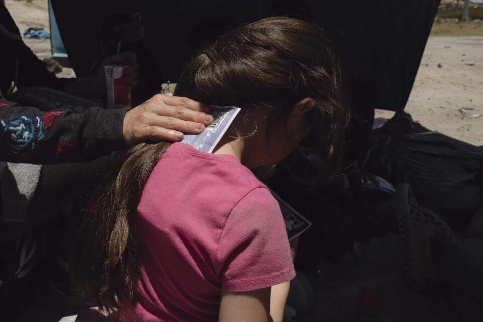 A woman places an ice pack against a young girls neck in an attempt to cool her off in the heat 