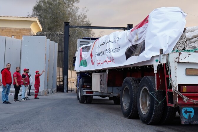 A supply truck has a banner with flags on its side.