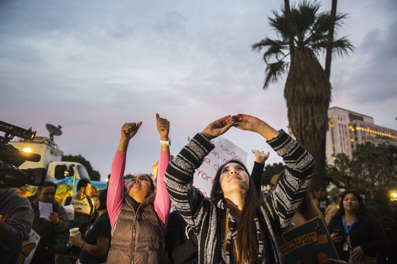 Nicole Paredes, 16, right, holds her hands in the air toward the Metropolitan Detention Center towards inmates looking through windows Thursday in downtown Los Angeles. Paredes was in the area for a rally and screening of President Obama addressing the nation with reformed immigration policy. 

President Obama addresses the nation with reforms in immigration policy in downtown Los Angeles on Thursday Nov. 20, 2014. 