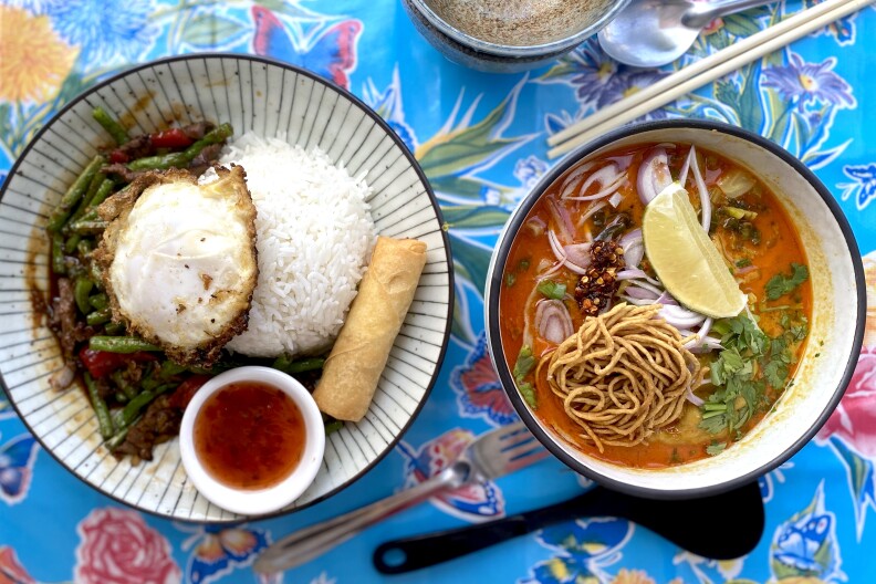 This bright and mouthwatering duo of Pad Nam Prik Pao consists of stir-fried beef topped with fried egg. Next to it on the left is a bowl of Khao Soi, a traditional Northern Thai curry noodle soup with a fragrant coconut milk–based broth.