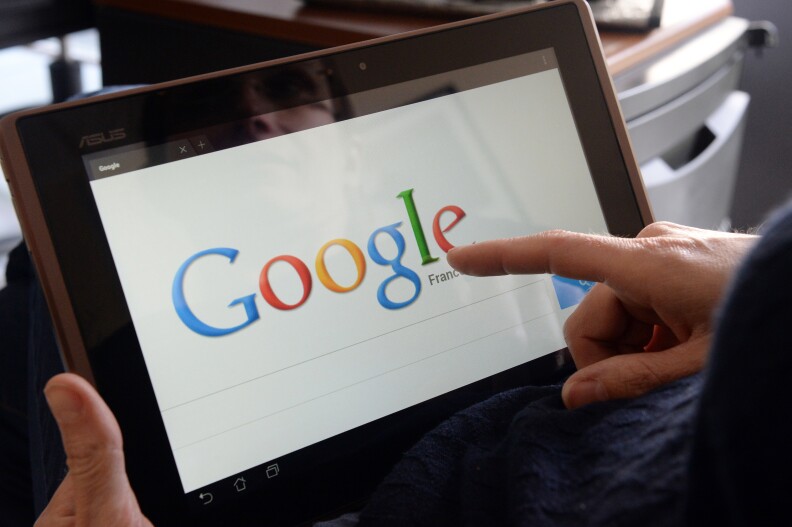 This picture taken on May 13, 2013 in the French western city of Rennes shows a woman choosing Google Search (or Google Web Search) web search engine front page on her tablet. 