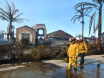 Firemen survey the damage to homes in the Anaheim Hills neighborhood on October 9, 2017, after the Canyon Fire 2 spread quickly through the area.
