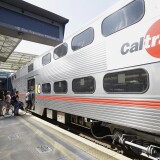 FILE  - In this July 1, 2013, file photo, commuters board a Caltrain train at the Caltrain and Bay Area Rapid Transit station in Millbrae, Calif. The Federal Transit Administration is delaying a decision on whether to approve a $650 million federal grant for electrification of a San Francisco Bay Area train system that would also help California's high-speed rail project. Congressional Republicans had pushed the administration to reject the application from Caltrain. (AP Photo/Jeff Chiu, File)