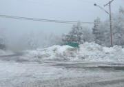 A sign pointing to Big Bear Lake and Lake Arrowhead is nearly covered in snow