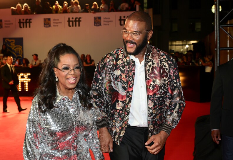 Oprah Winfrey and Typer Perry arrive on a red carpet in sparkly formal wear.
