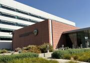 The exterior of a building has a terra cotta-colored stone wall with the words : County of Orange County Administration North 