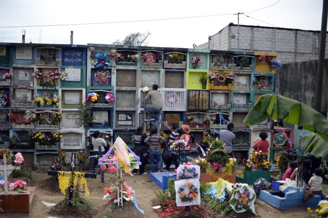 People adorn the resting place of relatives at the municipal cemetery of Villa Nueva, Guatemala during All Saints Day on November 1, 2016.