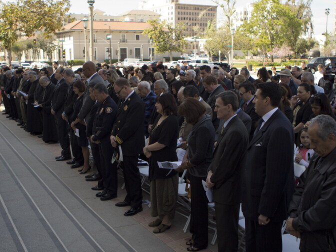 Commemoration attendees stand for a moment of silence.