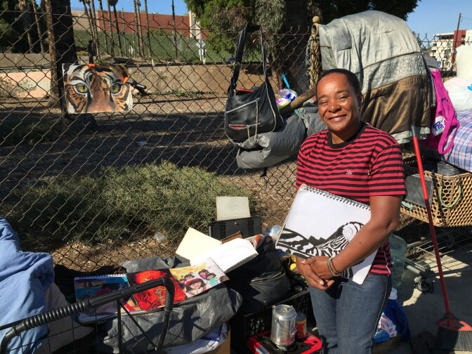 Skid row resident and artist Juanita Pina stands with some of her drawings