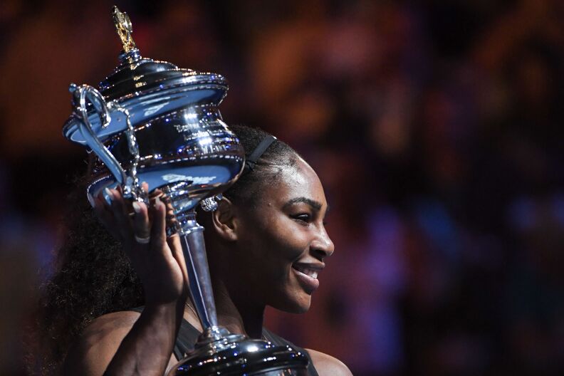 Serena Williams of the US celebrates with the championship trophy after her victory against her sister Venus in the women's singles final on day 13 of the Australian Open on January 28, 2017.