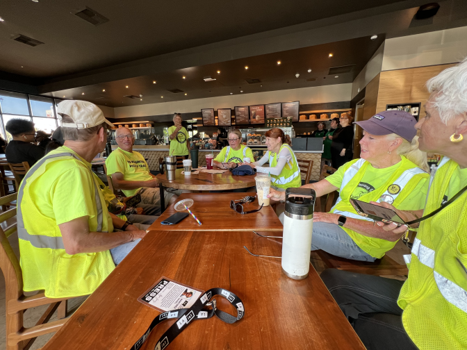 Eight members of the Volunteers Cleaning Communities gather around a table the Starbucks on Nordhoff Street after their cleaning session. Tables have been strung together to create a makeshift round table.