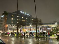 Dozens of protesters holding signs on a rainy night outside of a hospital.