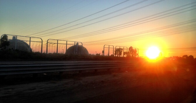 A public workshop Tuesday about safety and the storage of radioactive nuclear waste at the closed San Onofre nuclear plant is not as public as some activists would like it to be. (Photo: The sun sets behind the San Onofre Nuclear Generating Station in northern San Diego County).