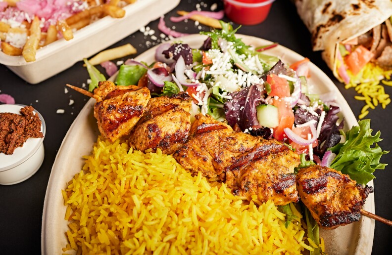 A kebab plate with a salad, kebab and saffron rice.