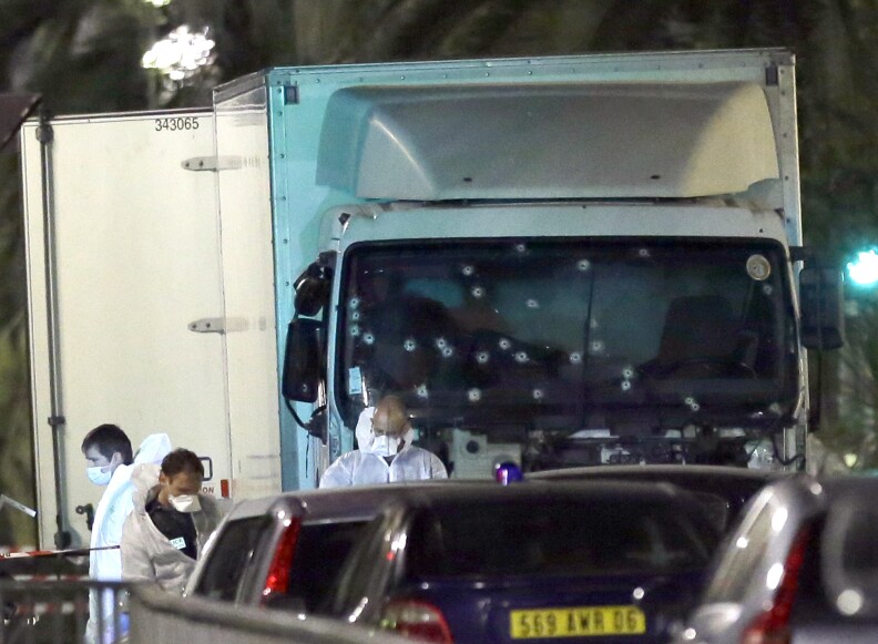 Forensic officers stands near a truck with its windscreen riddled with bullets, that plowed through a crowd of revelers who'd gathered to watch the fireworks in the French resort city of Nice, southern France, Friday, July 15, 2016. At least 80 people were killed before police killed the driver, authorities said. (AP Photo/Claude Paris)