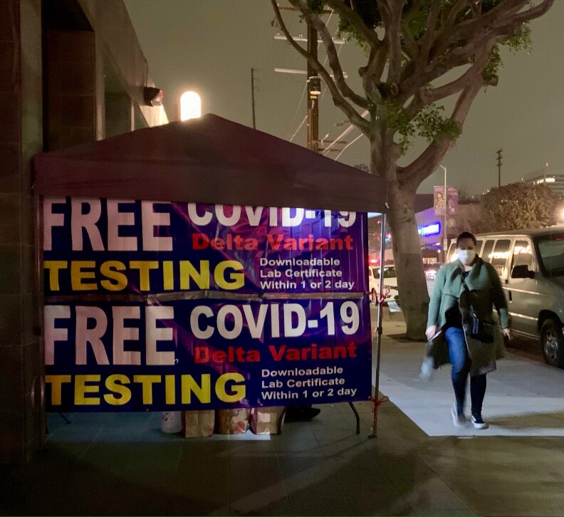 A woman walks by a tent that advertises free covid tests and mentions the Delta Variant.