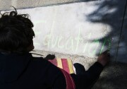 Dara Glanzer writes in chalk near the front entrance to the CSU Chancellor's office in Long Beach Wednesday. Glanzer was part of a coalition of students protesting a $280 per semester "Student Success Fee."