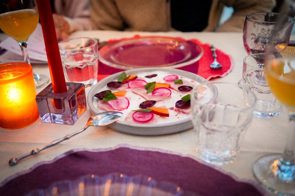 Paper-thin radish and beet slices scattered like confetti on a glowing table set for a long night