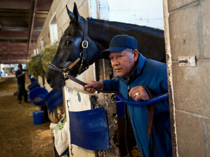 Assistant Trainer Ramon Gonzales stands in a stall with Top Knot, who is preparing for an afternoon race. Gonzales has worked at Cerin Racing Stables for 25 years.